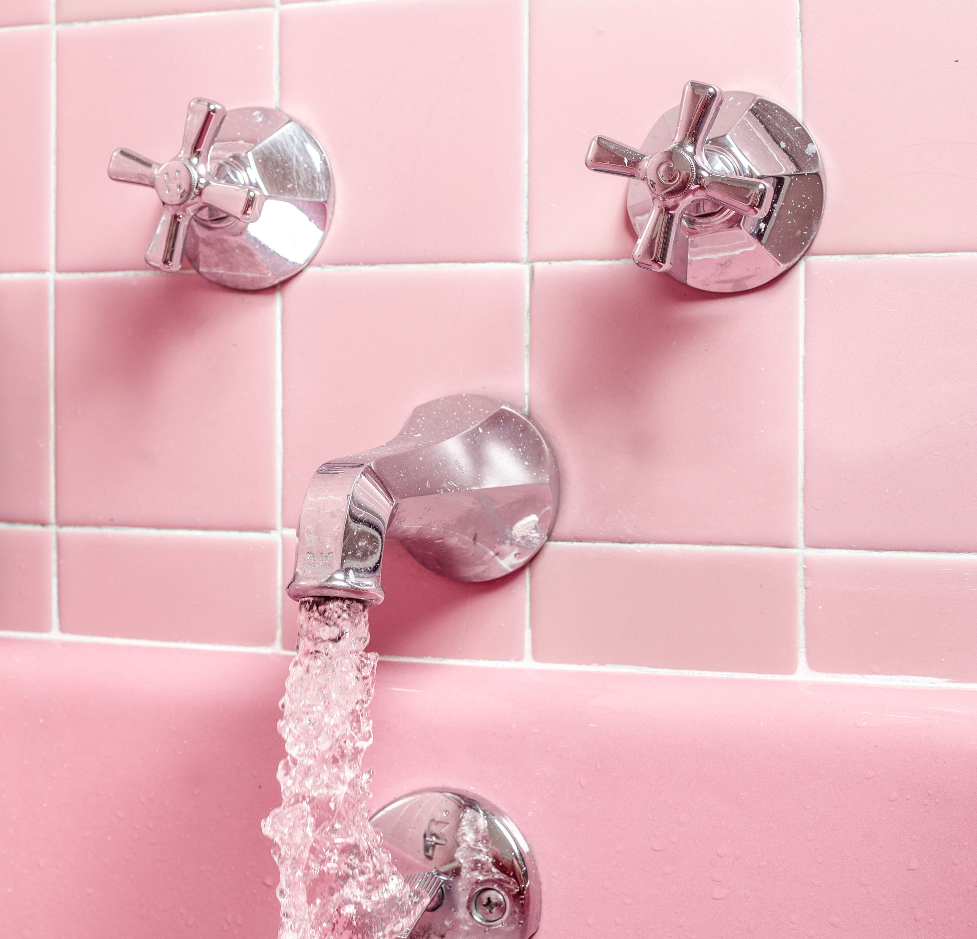 Pink tiled wall with taps, bathroom branding